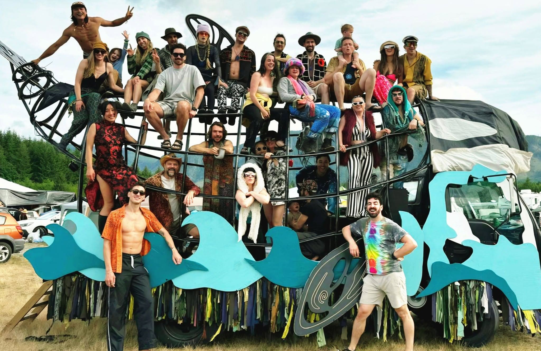 The Orcar build crew of ~30 community members posing on and inside the finished orca sculpture at a summer festival