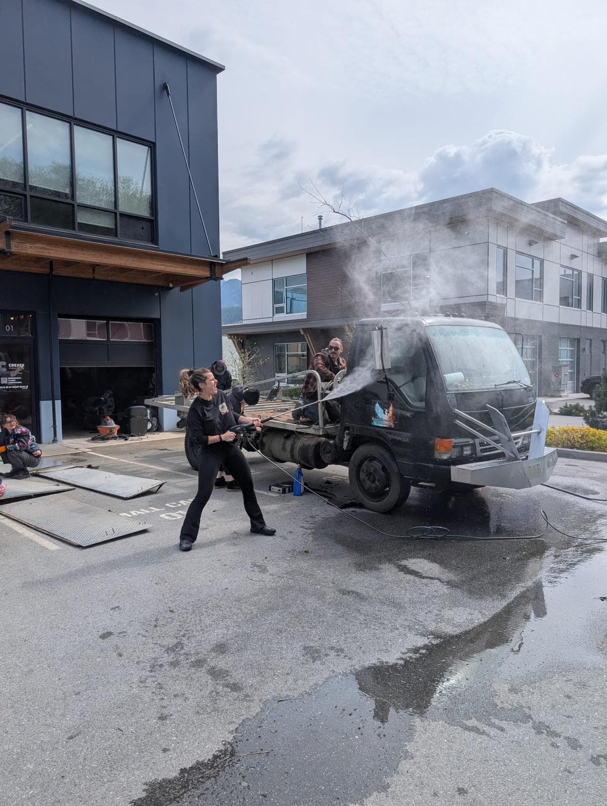 Team pressure-washing the Isuzu flatbed at Create Makerspace — prepping the truck for the Orcar build